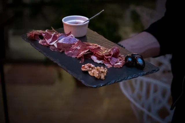Tabla de jamón serrano con nueces, aceitunas negras y salsa — fotografía gastronómica para un restaurante en Barcelona